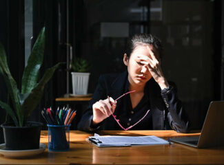 A woman office worker pinching her nose expressing stress