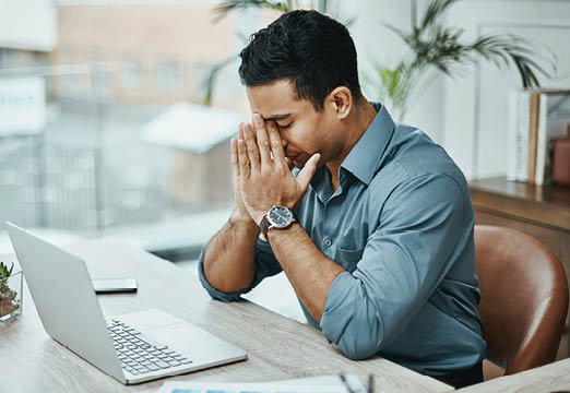 A business professional frowning at his laptop expressing stress