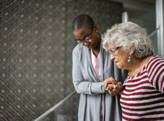 A younger adult helping an older adult down the stairs.