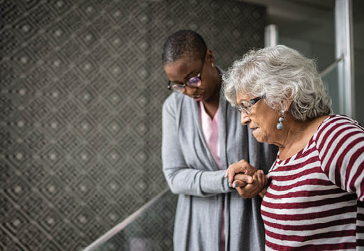 A younger adult helping an older adult down the stairs.